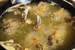 Floured chicken wings go into the hot oil